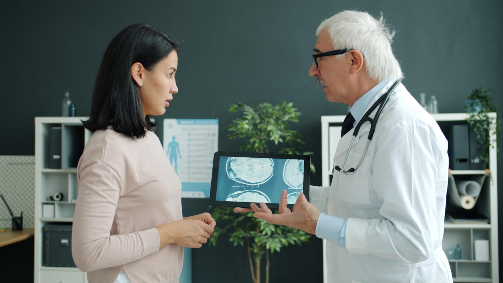 Médico explica un informe en una tableta a una paciente